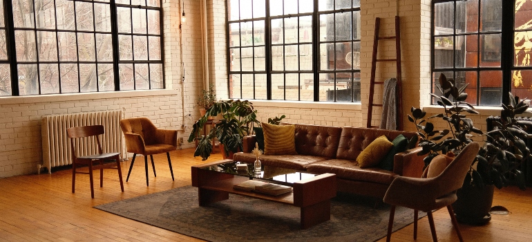 Loft style living room with brown leather sofa and movers in Roanoke, VA preparing for a local relocation.