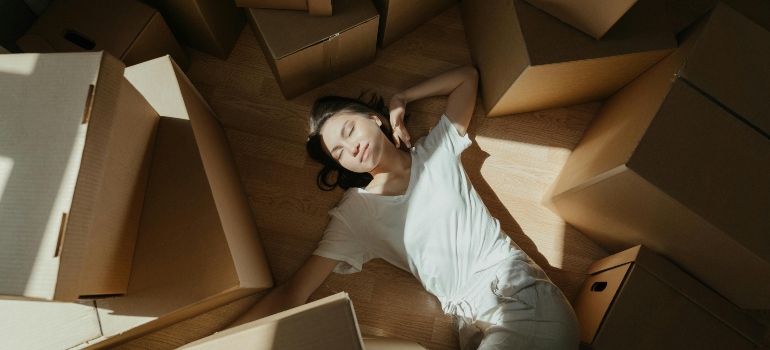 a woman resting on the floor among moving boxes