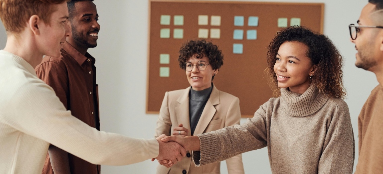 Cave Springs movers shaking hands with clients near a white wall, marking the start of a successful moving day.