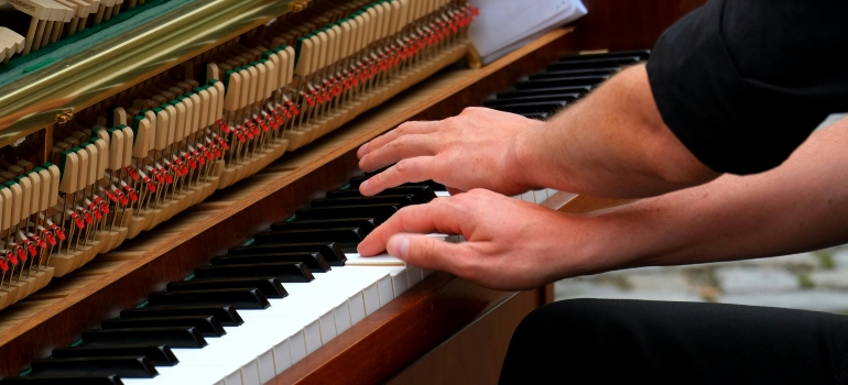 Close-up of pianist’s hands playing a classic piano with exposed strings.