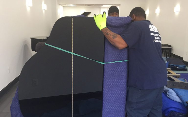 Ace movers wrapping a grand piano with moving pads and straps