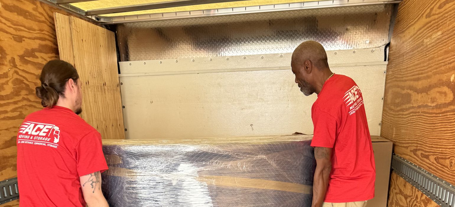 Two Ace movers lifting a wrapped table into a moving truck for a local move in Virginia